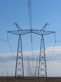 Low angle view of electricity pylon on field against sky