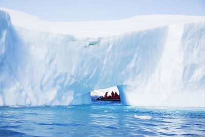 Tourists at natural ice arch on sea