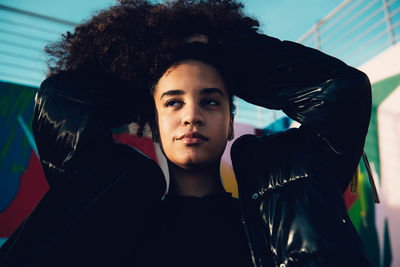 Stylish african american female with afro hairstyle in trendy black outfit standing on the street