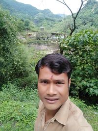 Portrait of smiling man standing against plants