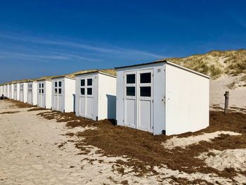 Built structure on beach by houses against clear blue sky