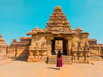 Rear view of woman standing outside temple against building