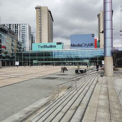 Footpath by buildings against sky in city