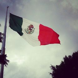 Low angle view of american flag against cloudy sky