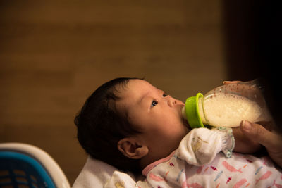 Cropped hand feeding baby using milk bottle at home