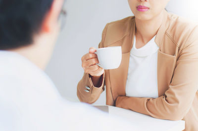 Rear view of man with friend holding coffee on table