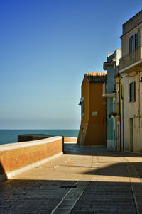 Building by sea against clear blue sky