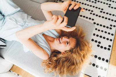 High angle view of woman using mobile phone while sitting on bed at home