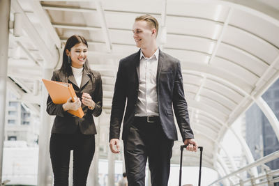 Coworkers talking while walking on footbridge in city