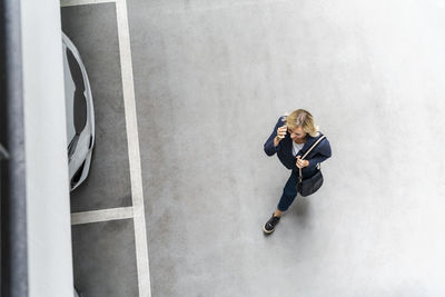 Mature businesswoman talking on phone walking at parking lot