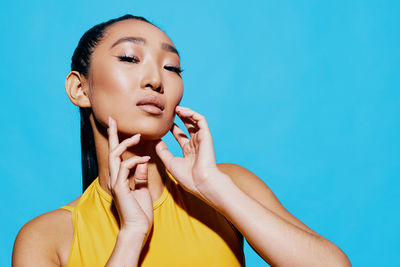 Portrait of young woman against blue background