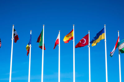 Low angle view of flags against clear blue sky