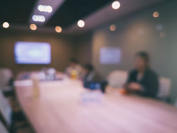 Defocused image of people sitting on table