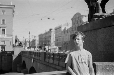 Low angle view of young man standing  near a bridge 