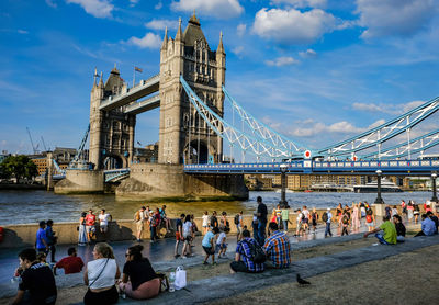 Group of people at bridge against cloudy sky