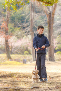 Portrait of man with dog standing against trees