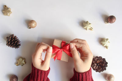 Cropped hands of woman holding christmas decorations on table