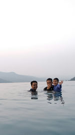 Portrait of smiling siblings swimming in sea