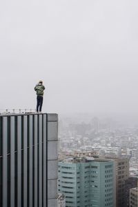 Man standing by cityscape against clear sky