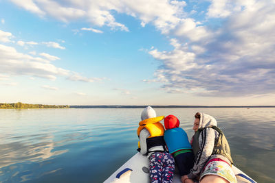 Family sitting in boat against sky