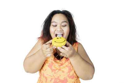 Woman eating donut against white background
