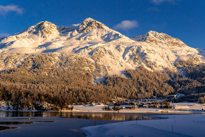 View of beautiful snow mountains behind lake silvaplana and its village in switzerland during winter