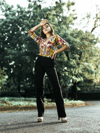 Full length portrait of young woman standing on road