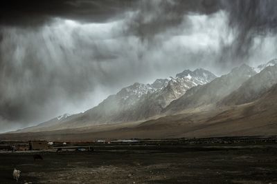 The towering snow-capped mountains next to the alar wetland are about to be covered by storm