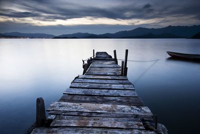 Pier over lake against sky at sunset