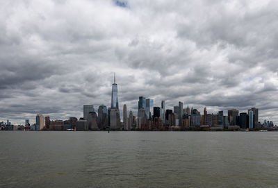 Sea by modern buildings against sky in city