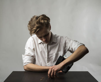 Young woman sitting on table against wall