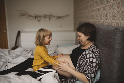 Pregnant woman and daughter touching belly