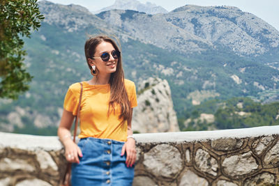 Young woman wearing sunglasses standing on railing