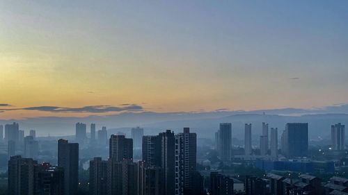 Skyscrapers in city against sky during sunset