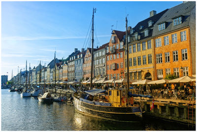 Buildings by river against sky