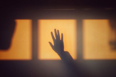 Close-up of hand touching shadow on wall