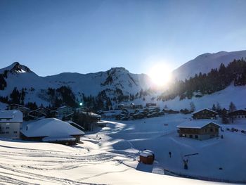 Snow covered houses and mountains against sky