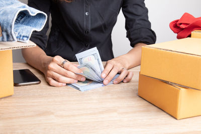 Midsection of man holding paper while sitting on table