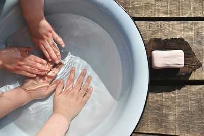 High angle view of a bowl of water with 4 childish hands in it