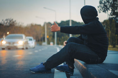 Side view of man on street against sky