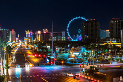 Illuminated road and buildings against clear sky at night