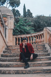 Portrait of man sitting on staircase against building