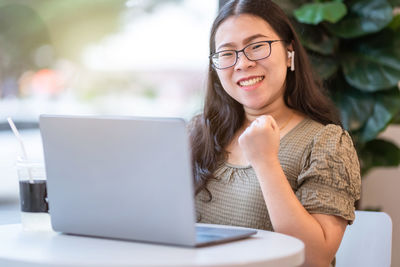 Young woman using mobile phone while sitting on table