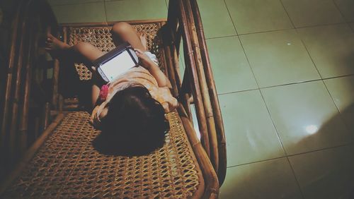 High angle view of girl with mobile phone on chair at home