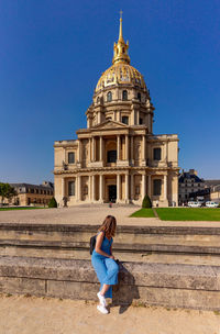 Woman sitting outside temple against blue sky