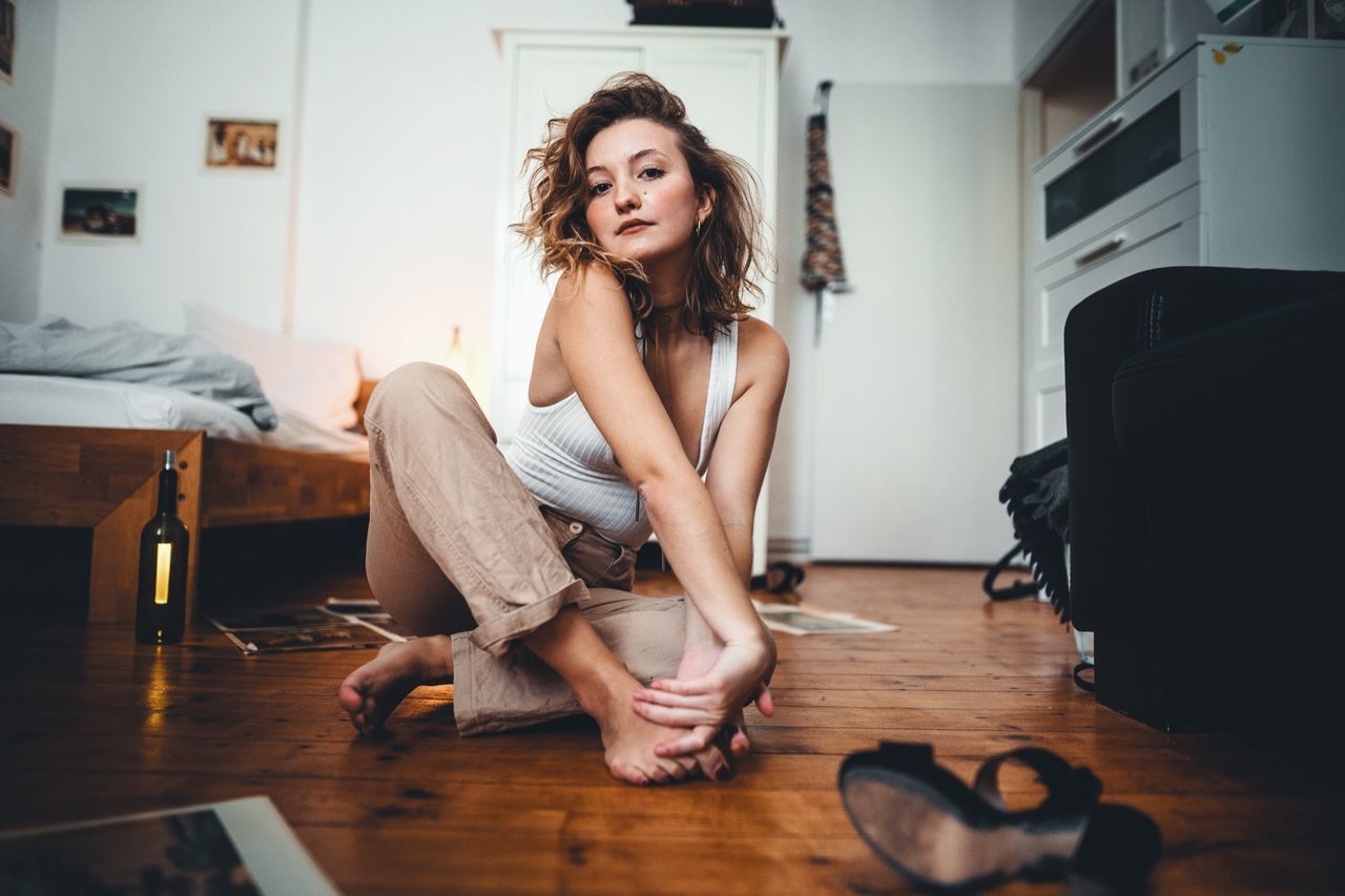 WOMAN SITTING ON HARDWOOD FLOOR AT HOME