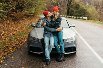 A couple in love on an autumn day hugging on the road near the car.