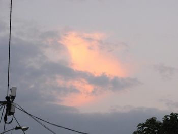 Low angle view of power lines against cloudy sky