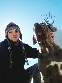 Portrait of young man with bull mastiff against clear sky