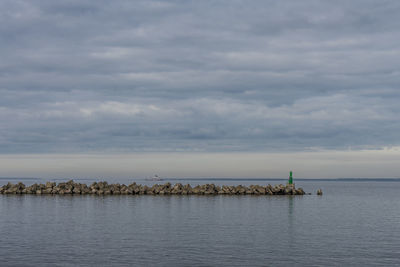 Birds perching on sea against sky